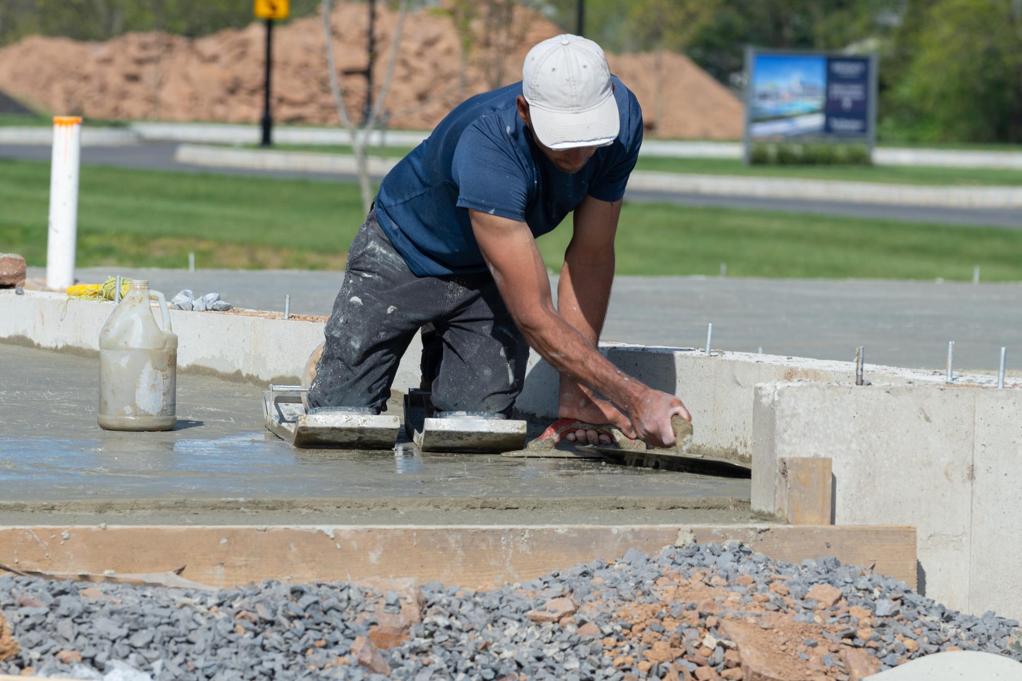 Béton désactivé pour cour carrossable : Prix, épaisseur et avantages 2 maçon réalisant la mise à niveau d'une dalle béton désactivé pour cour carrossable